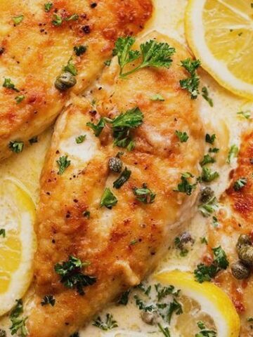 close up of chicken sauteed in a creamy lemony sauce topped with capers and parsley