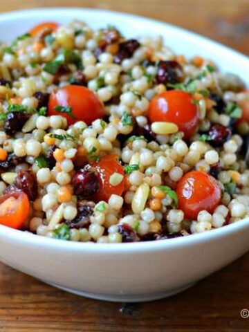 White bowl filled with Israeli couscous, diced cherry tomatoes
