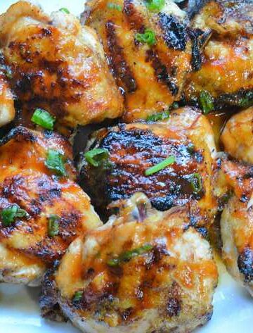 Grilled huli huli chicken on white platter with scallions