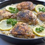 Large cast iron skillet chicken thighs lemon pepper risotto garnished with lemons