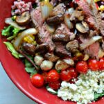 close up caprese steak salad sauteed mushrooms onions, lettuce, tomatoes, bacon in reduced balsamic dressing