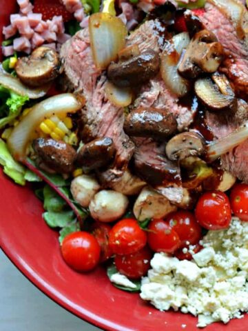 close up caprese steak salad sauteed mushrooms onions, lettuce, tomatoes, bacon in reduced balsamic dressing