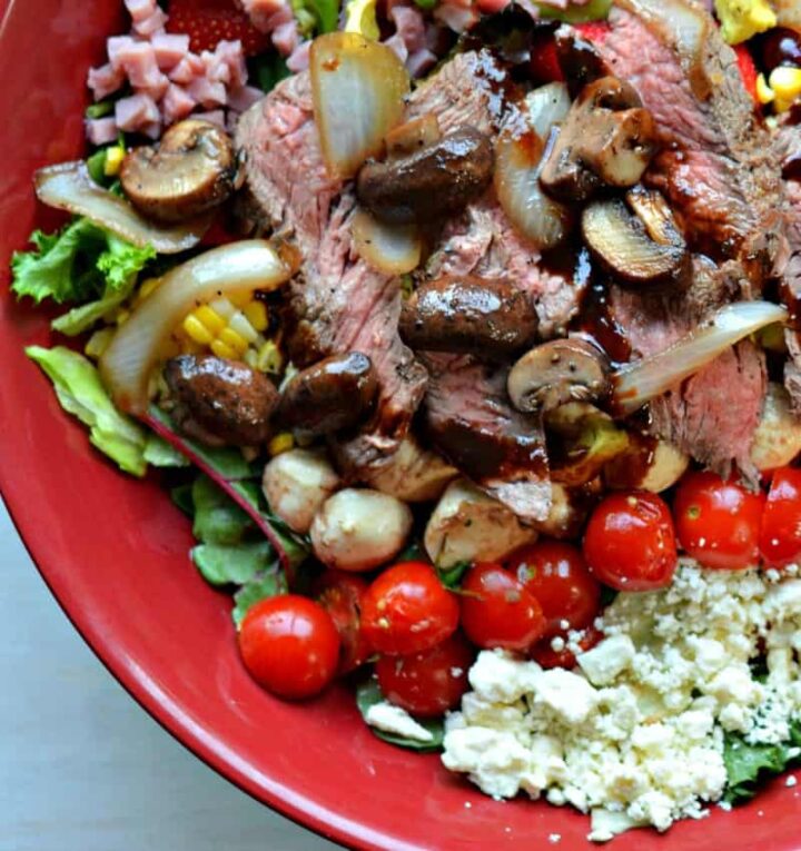 close up caprese steak salad sauteed mushrooms onions, lettuce, tomatoes, bacon in reduced balsamic dressing