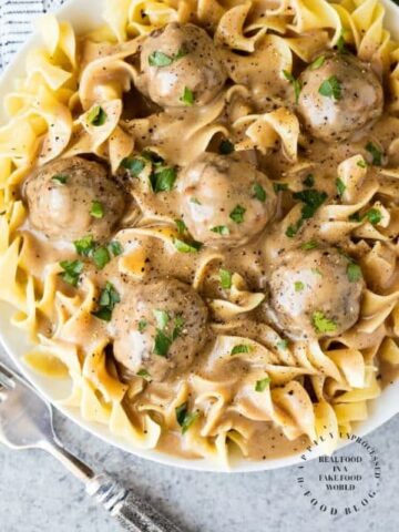 overshead shot swedish meatballs over large egg noodles in white bowl