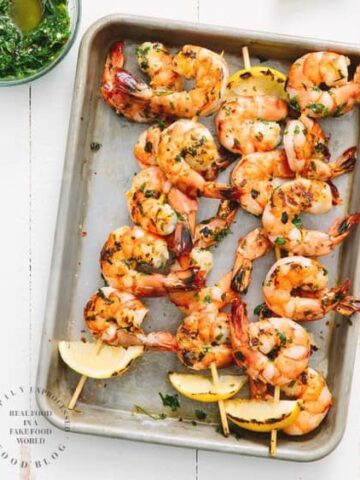 grilled shrimp on skewers on baking sheet with charred lemon