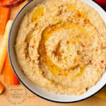roasted red pepper hummus in bowl with extra olive oil with carrots