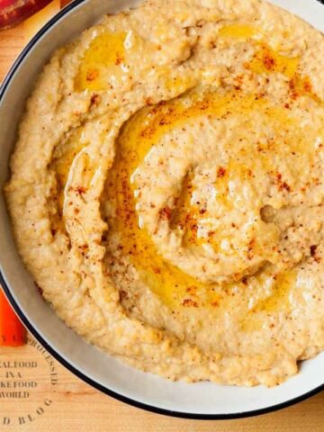 roasted red pepper hummus in bowl with extra olive oil with carrots