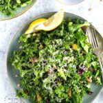 An easy lemony garlic kale salad with pistachios, pine nuts, dried cranberries topped with shaved parmesan cheese #newyearsresolution #kale #salad #healthy #happilyunprocessed