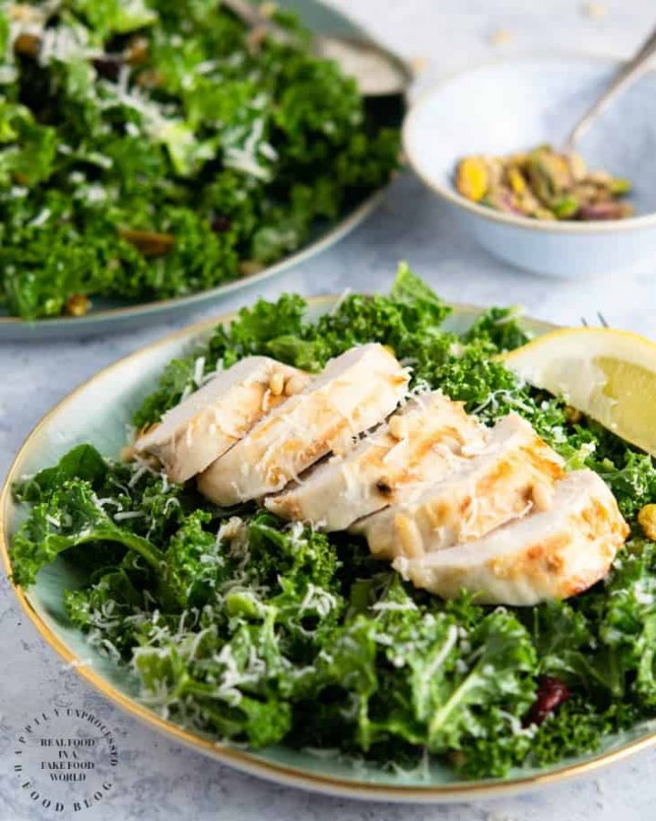 An easy lemony garlic kale salad with pistachios, pine nuts, dried cranberries topped with shaved parmesan cheese #newyearsresolution #kale #salad #healthy #happilyunprocessed