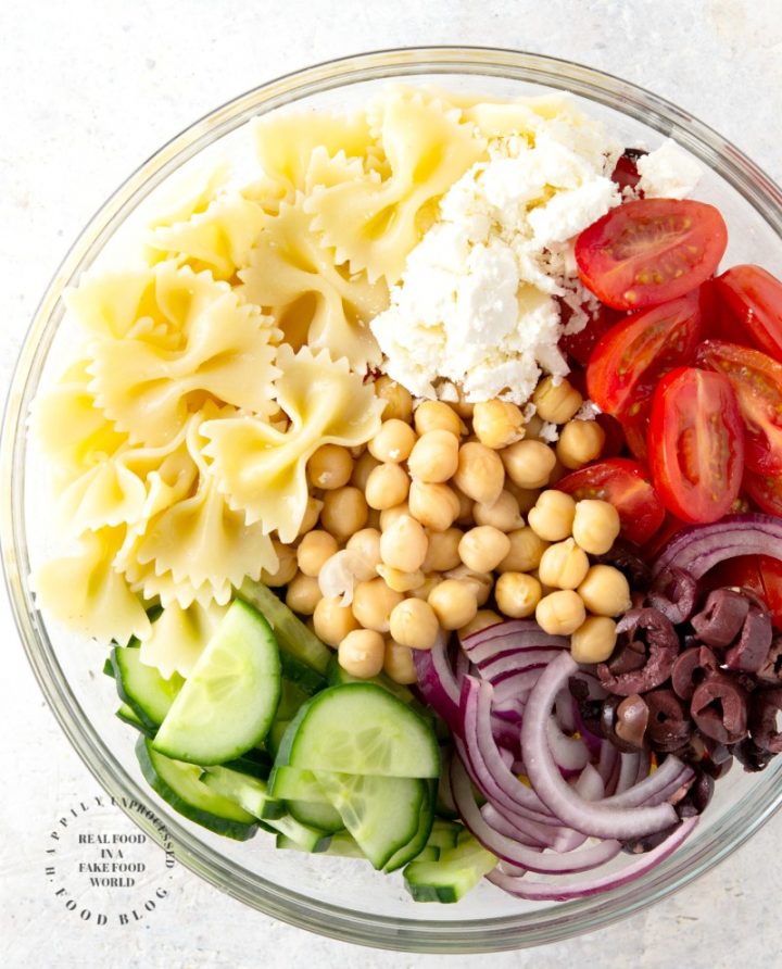 MEDITERRANEAN PASTA SALAD with bowtie pasta, red onion, cucumbers, cherry tomatoes, chick peas and feta cheese in a lemony vinaigrette #pastasalad #summer #sidedish #healthysidedish #happilyunprocessed