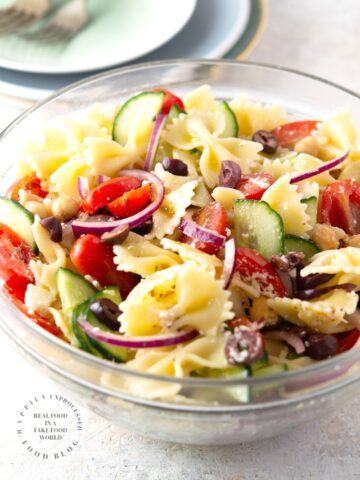 MEDITERRANEAN PASTA SALAD with bowtie pasta, red onion, cucumbers, cherry tomatoes, chick peas and feta cheese in a lemony vinaigrette #pastasalad #summer #sidedish #healthysidedish #happilyunprocessed