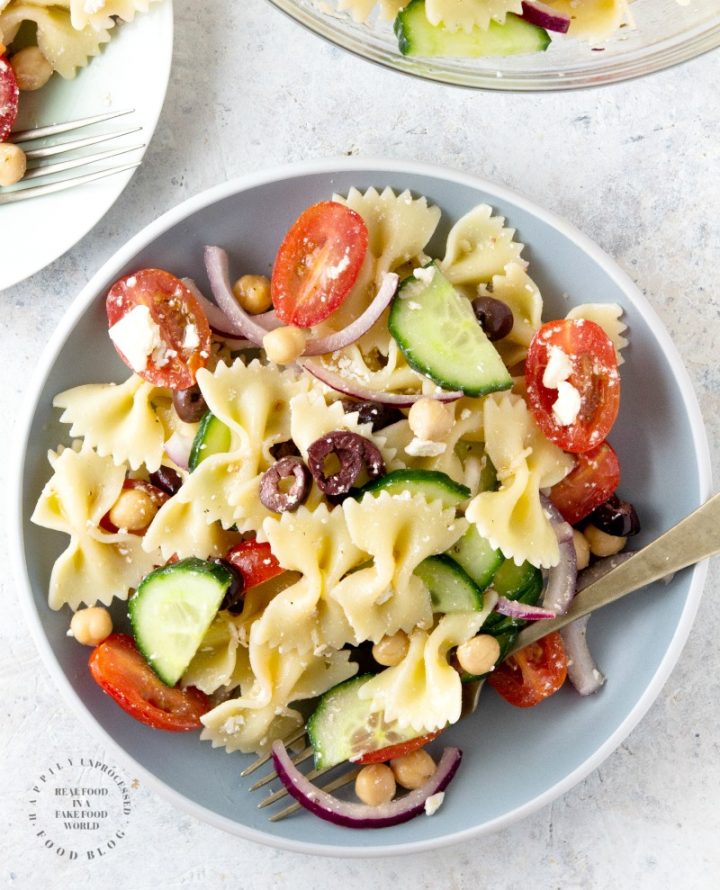 MEDITERRANEAN PASTA SALAD with bowtie pasta, red onion, cucumbers, cherry tomatoes, chick peas and feta cheese in a lemony vinaigrette #pastasalad #summer #sidedish #healthysidedish #happilyunprocessed