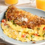Hash Brown Wrapped Vegetarian Omelet - crispy golden hash browns form a perfect shell to wrap an omelet on the inside #breakfastfood #eggs #potatoes #hashbrowns #happilyunprocessed.com