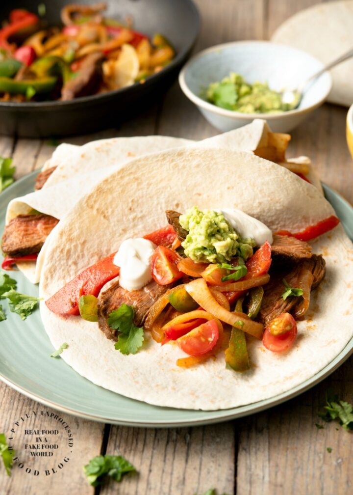 FLANK STEAK FAJITAS - perfectly grilled strips of flank steak with onions and peppers served with fresh tortillas, sour cream, guacamole and salsa #fajitas #happilyunprocessed