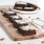 Healthy chocolate zucchini brownies with powdered sugar on top on cutting board