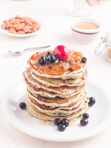 Homemade Blueberry Buttermilk Pancakes in a stack on a plate with fresh fruit