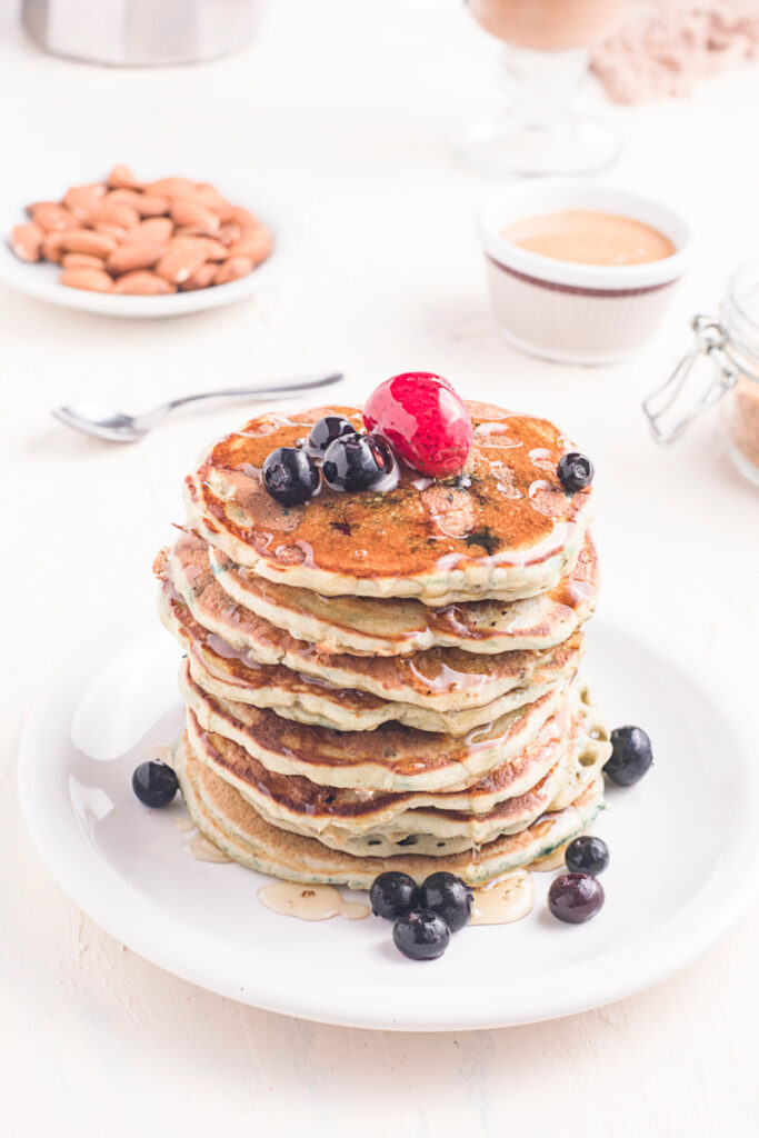 Homemade Blueberry Buttermilk Pancakes in a stack on a plate with fresh fruit