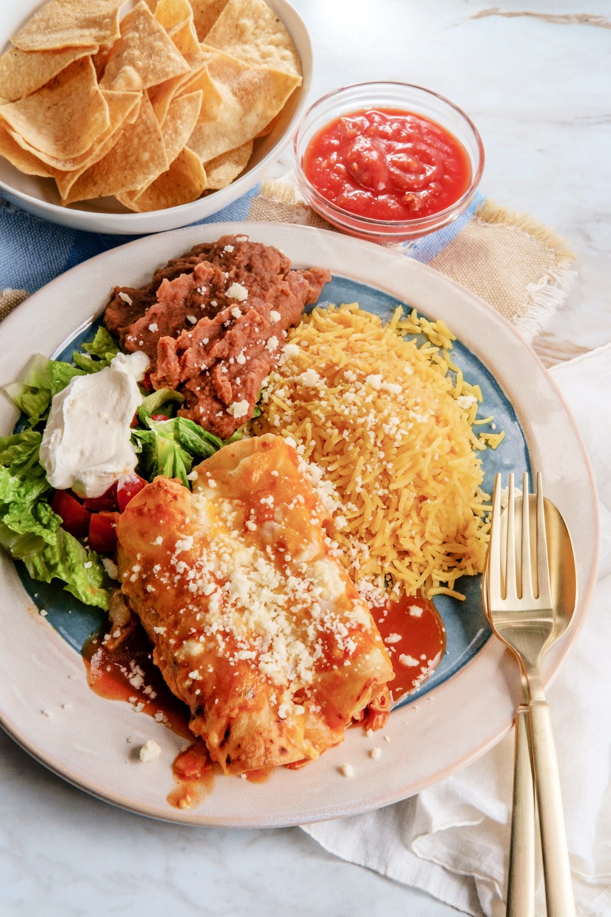 Traditional Mexican chicken enchiladas dinner served with rice and refried pinto beans