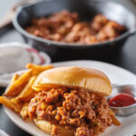 sloppy joe sandwich piled high on a toast bun with ground beef pepper and onions in a tomato sauce