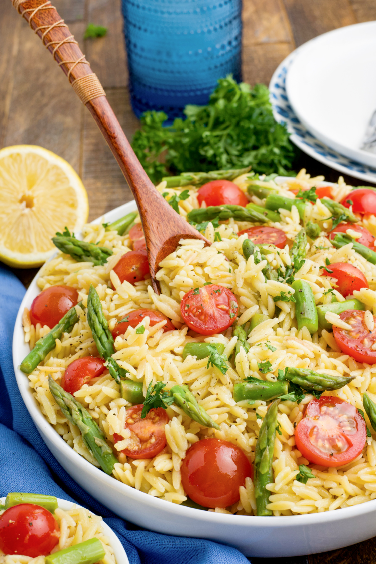 Lemon Orzo with tomatoes and asparagus with a wooden spoon in a large bowl