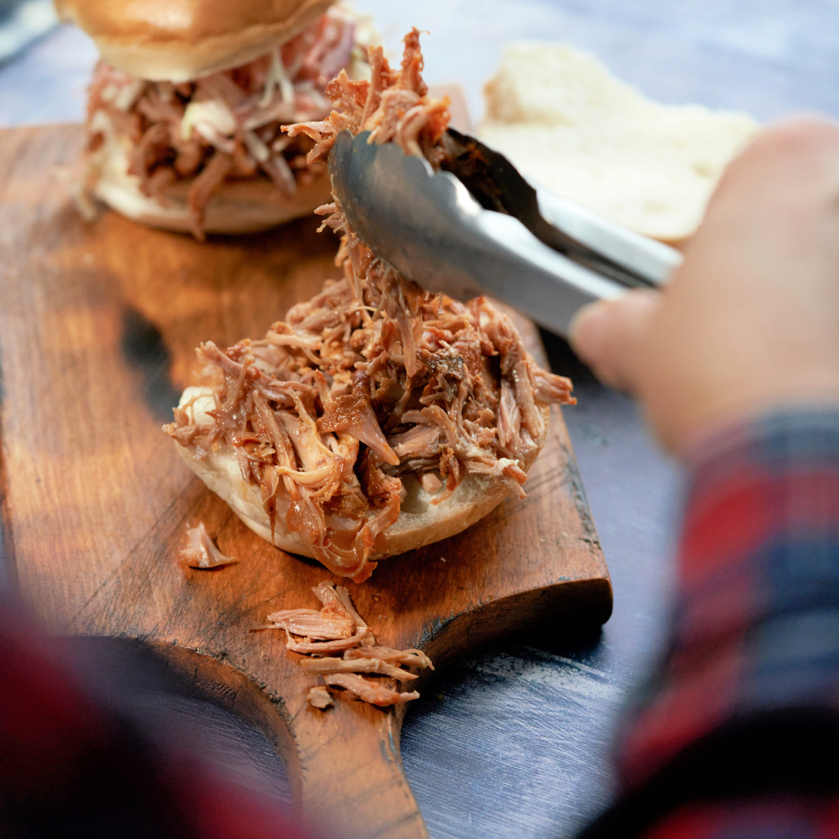 Pulled pork shredded and being put on a toasted bun with BBQ sauce