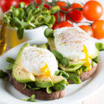 a perfectly poached egg with fresh avocado on toast
