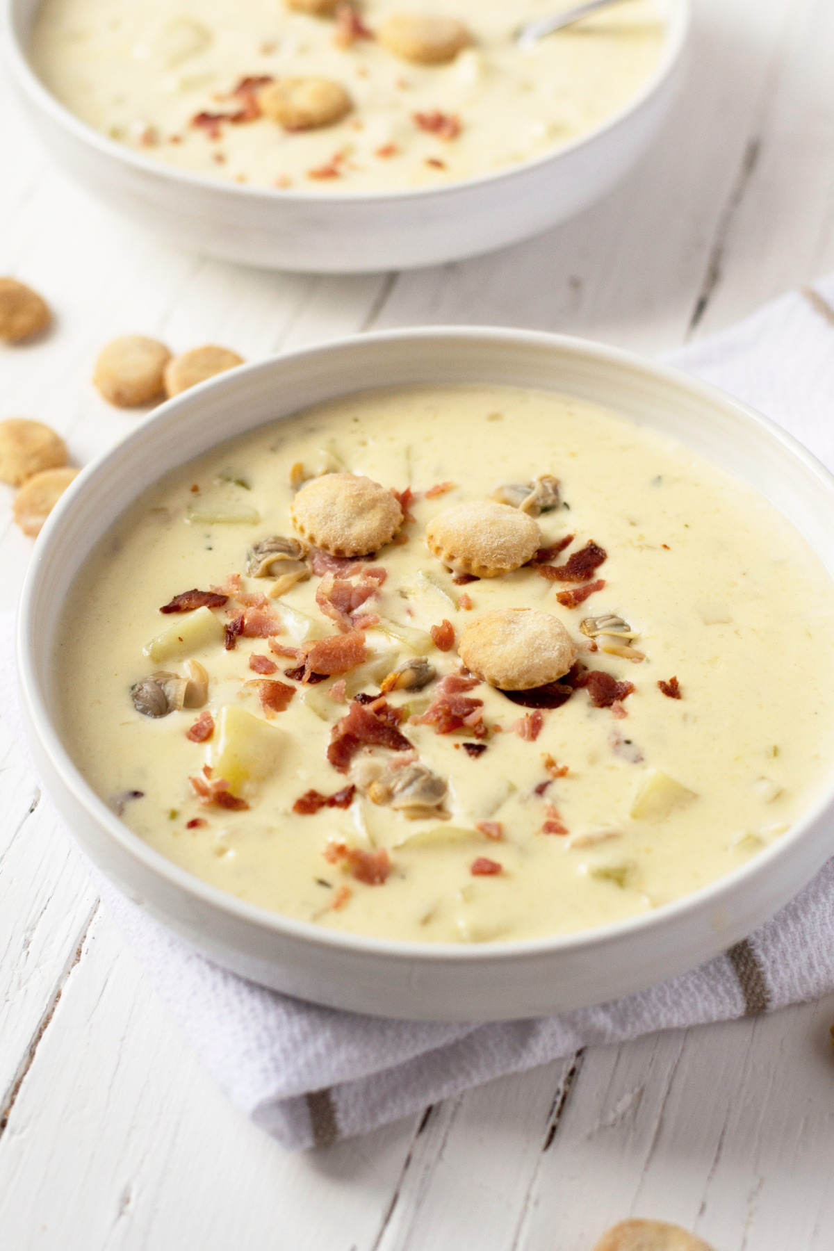 A big bowl of homemade New England Clam Chowder with oyster crackers and bacon on top