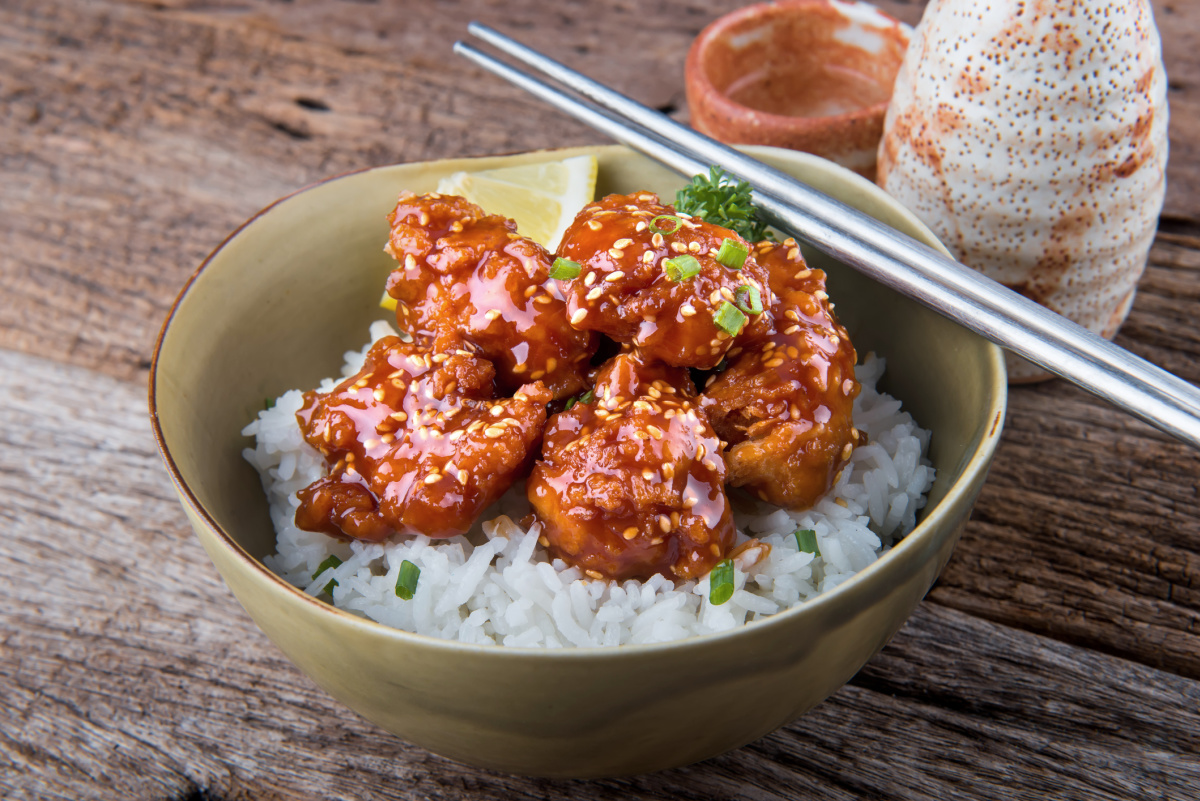 Sesame chicken in a sweet and sticky sauce on top of rice