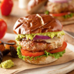 turkey burger on a pretzel bun with onions and guacamole