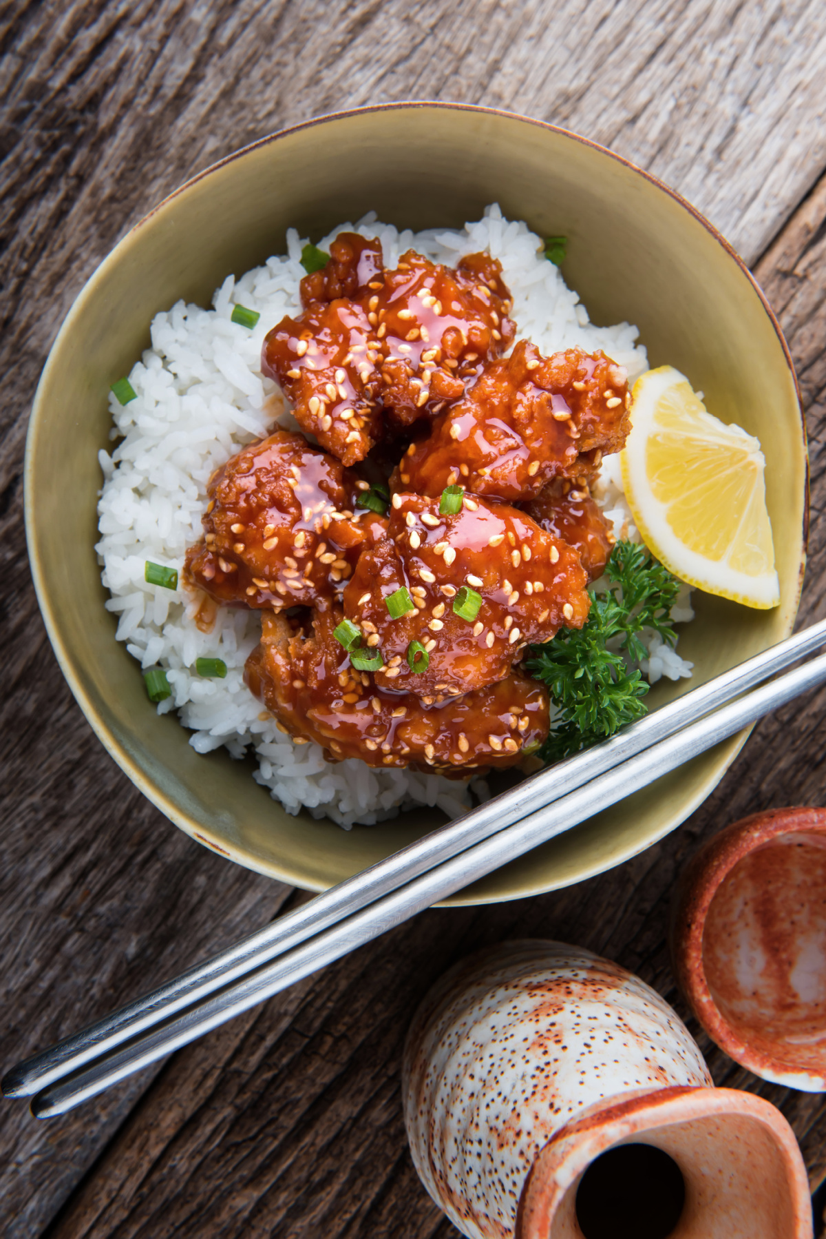 A plate with crispy chunks of chicken coated in a honey sesame sauce with sesame seeds on top