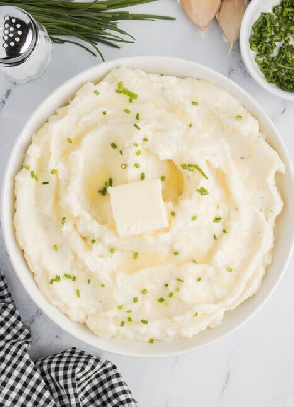 A bowl of creamy garlic mashed potatoes with fresh chives on top