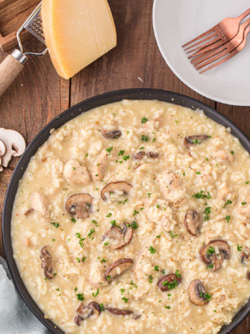 Large skillet of mushroom risotto with chunks of chicken